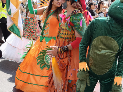 Farbfoto von einem als Frosch verkleideten Menschen in der Samba-Gruppe SAPUCAIU NO SAMBA auf dem Umzug vom Karneval der Kulturen auf der Straße Hasenheide in Berlin am 28. Mai 2023. Fotograf: Erwin Thomasius.