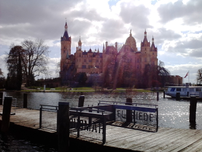 Farbfoto: Blick von der Anlegestelle für Fahrgastschiffe der Reederei WEISSE FLOTTE Schwerin aus auf das Schloss Schwerin auf der Schlossinsel im Schweriner See in Schwerin im April des Jahres 2015. Fotograf: R.I.